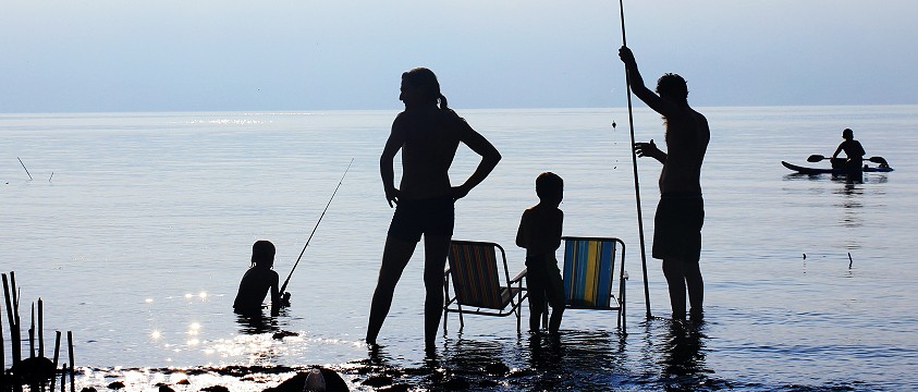 family silhouetted against water