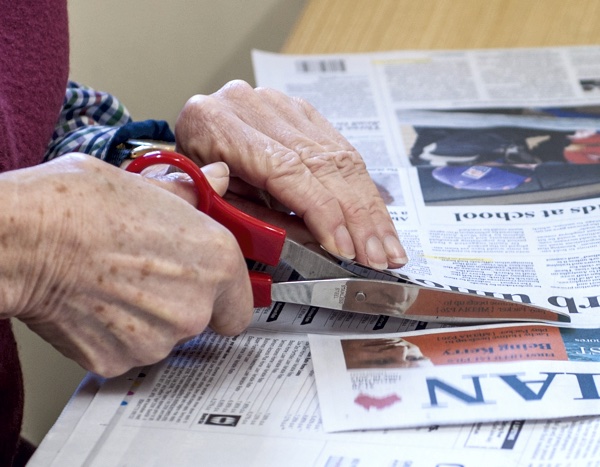 closeup of hands, scissors, cutting newspaper