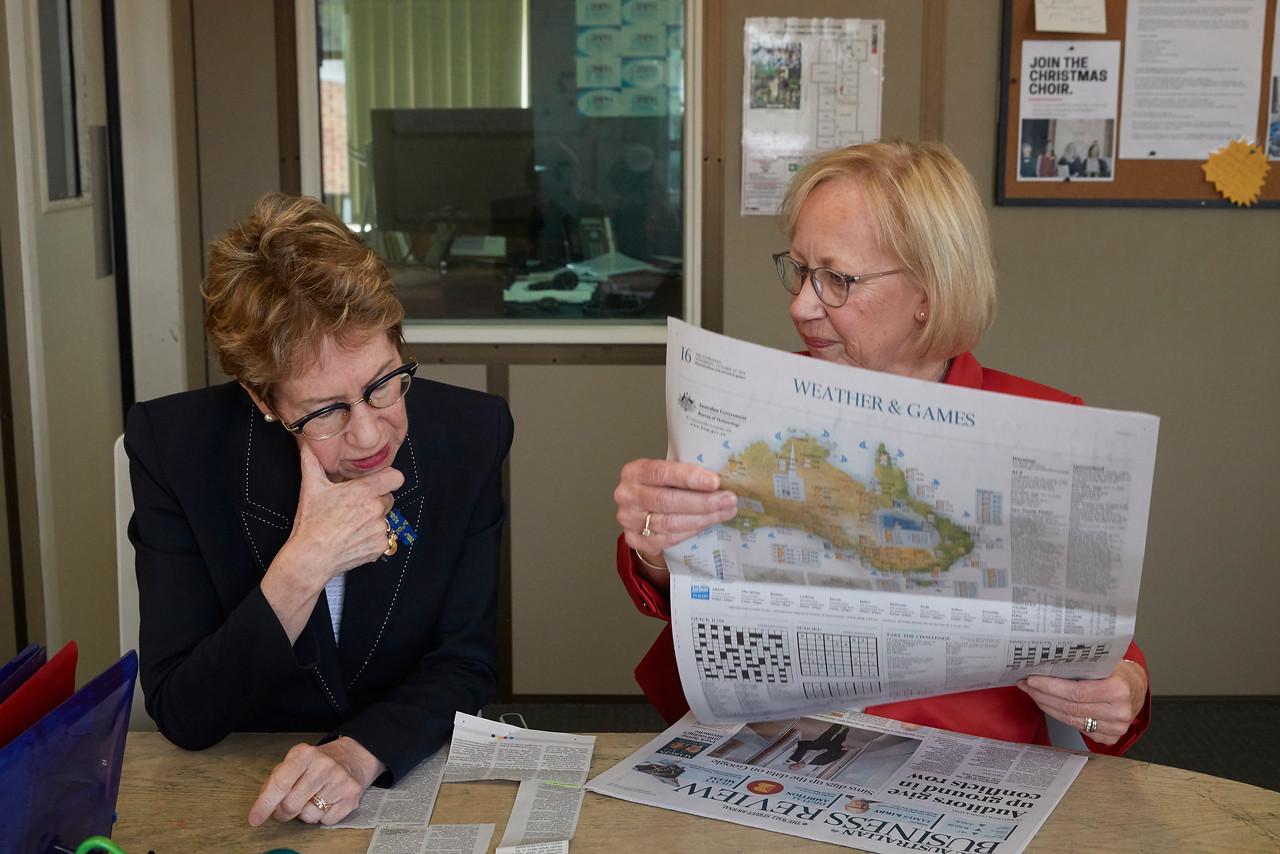 The Governor sitting next to volunteer Janet while reviewing The Australian newspaper.